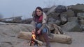 Young woman sitting near the fire in the evening fire.