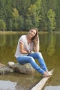 Young woman sitting near a lake.