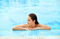 Young woman sitting near the pool. Sexy girl with healthy tanned skin. Female with sun hat relaxing in swimming pool Royalty Free Stock Photo