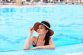 Young woman sitting near the pool. Sexy girl with healthy tanned skin. Female with sun hat relaxing in swimming pool Royalty Free Stock Photo