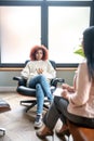 Young woman sitting near window and talking to psychoanalyst