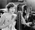 Young woman sitting next to a fan and a thermometer looking hot and eating an ice cream Royalty Free Stock Photo