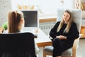 Young woman sitting in office during the job interview with female employee, boss or HR-manager, talking, thinking