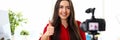 Young woman sitting in office opposite camera and showing good luck thumb finger up Royalty Free Stock Photo