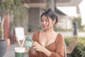 A young woman sitting outside the cafe is texting her friends with her cellphone Royalty Free Stock Photo