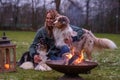 Young woman is sitting outside in the woods with her two Australian Shepherd dogs. Snow on the grass, twilight by the
