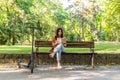 A young woman is sitting on a park bench with the book in her hands Royalty Free Stock Photo