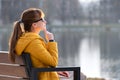 Young woman sitting on park bench relaxing on warm spring day