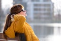 Young woman sitting on park bench relaxing on warm spring day