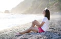 Young woman sitting at pebble beach at Mediterranean sea