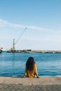 Young woman sitting on pier and looking away Royalty Free Stock Photo