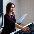 Young woman sitting and playing on the electronic piano Royalty Free Stock Photo