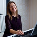 Young woman sitting and playing on the electronic piano Royalty Free Stock Photo