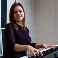 Young woman sitting and playing on the electronic piano Royalty Free Stock Photo
