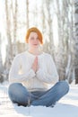 Young woman sitting and praying in winter forest Royalty Free Stock Photo