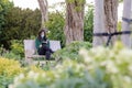 A young woman sitting reading a book in a park in UK England during pandemic outbreak of coronavirus Royalty Free Stock Photo