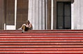 Young woman sitting and reading book on red stairs in front of Federal Hall in front the front, wall street, Manhattan, New York C Royalty Free Stock Photo