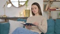 Young Woman Sitting Reading Book on Sofa Royalty Free Stock Photo