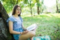 Young woman sitting and reading her favorite book on a o green gras under tree in a nice sunny summer Royalty Free Stock Photo