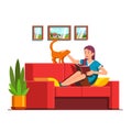 Woman sitting on sofa, reading book, petting cat Royalty Free Stock Photo