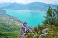 A young woman sitting on the rock and admiring a panoramic view on the Lake Annecy