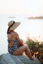 Young woman sitting on the rock by the sea enjoying sunset Royalty Free Stock Photo