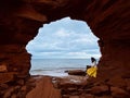 Young woman sitting on rocks under the sea cliffs at Cavendish Beach, Prince Edward Island, Canada Royalty Free Stock Photo