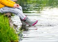 A young woman is sitting in rubber boots by the lake