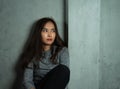 Young woman sitting sad against wall, depression emotion, looking above space in dark room, Portrait of young beautiful woman or Royalty Free Stock Photo