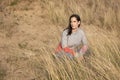 Young woman sitting among sand dunes