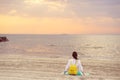 Young woman sitting on a sandy beach looking at sea and sunset Royalty Free Stock Photo