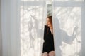 Young woman sitting on a sill in short sexy black robe, showing bra she took off Royalty Free Stock Photo