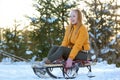 Young woman sitting on a sledge in the forest. Winter holidays