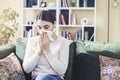 Young woman sitting on sofa covered  freezing blowing running nose got fever caught cold sneezing in tissue, sick girl having infl Royalty Free Stock Photo