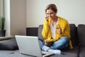 Young woman drinking beer and eating nachos while watching movie on her laptop at home Royalty Free Stock Photo