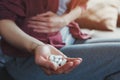 Young woman sitting on sofa with hand on aching stomach holding white medicine pills Royalty Free Stock Photo