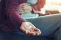 Young woman sitting on sofa with hand on aching stomach holding white medicine pills Royalty Free Stock Photo