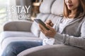 Young woman sitting on sofa at living room and using cell phone Royalty Free Stock Photo