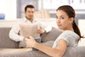 Young woman sitting on sofa man in background Royalty Free Stock Photo