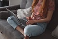 Young woman sitting on sofa and using laptop Royalty Free Stock Photo