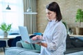 Young woman sitting on sofa using laptop for work, freelancing, learning Royalty Free Stock Photo