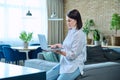 Young woman sitting on sofa using laptop for work, freelancing, learning Royalty Free Stock Photo