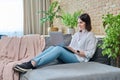 Young woman sitting on sofa using laptop for work, freelancing, learning Royalty Free Stock Photo