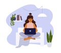 Young woman sitting on sofa and working or studying from home using laptop