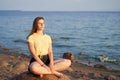 Young woman sitting on the stone on the seaside. Relaxing. Slowing down.