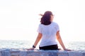 Young woman sitting on stone wall watching the sunset over the ocean Royalty Free Stock Photo