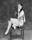 Young woman sitting on a stool holding a vanity mirror Royalty Free Stock Photo