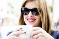 Young woman is sitting at the street cafe, drinking coffee and smiling in springtime. Royalty Free Stock Photo