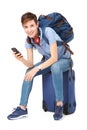 Young woman sitting on suitcase with mobile phone in hand Royalty Free Stock Photo