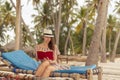 Woman sitting on sun bed on tropical beach, reading a book Royalty Free Stock Photo